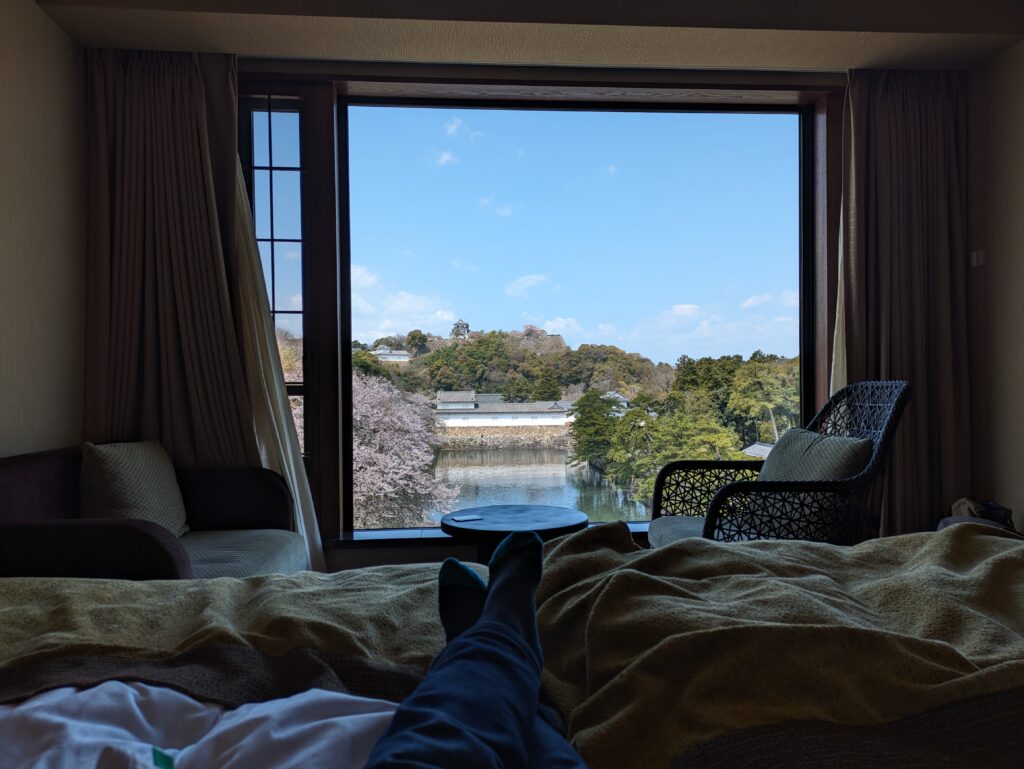 彦根キャッスル リゾート&スパでベッドに寝転がりながら窓の景色を楽しむ私